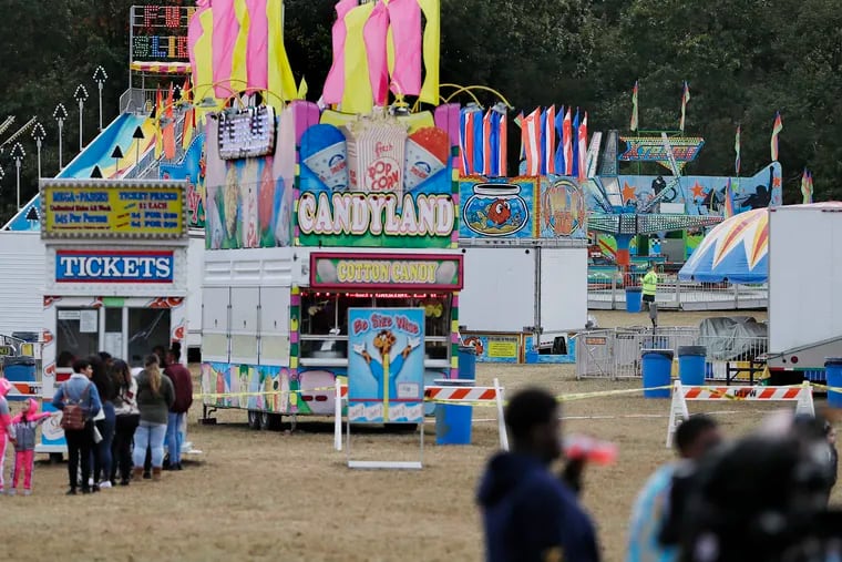 People line up to get their money back for ride wristbands (left) as men watch the amusement ride “Xtreme” on the far right at the Deerfield Township Harvest Festival. A 10-year-old girl was killed after being ejected from the ride, police said.
