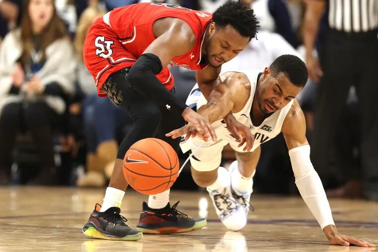 Phil Booth, right, of Villanova dives to try an steal the ball away from Shamorie Ponds of St. John’s during the 2nd half at Finneran Pavilion on Jan. 8, 2019.    