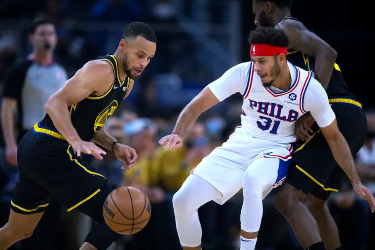 Golden State Warriors guard Stephen Curry attempts to drive past his brother and Sixers guard Seth Curry during the first quarter.