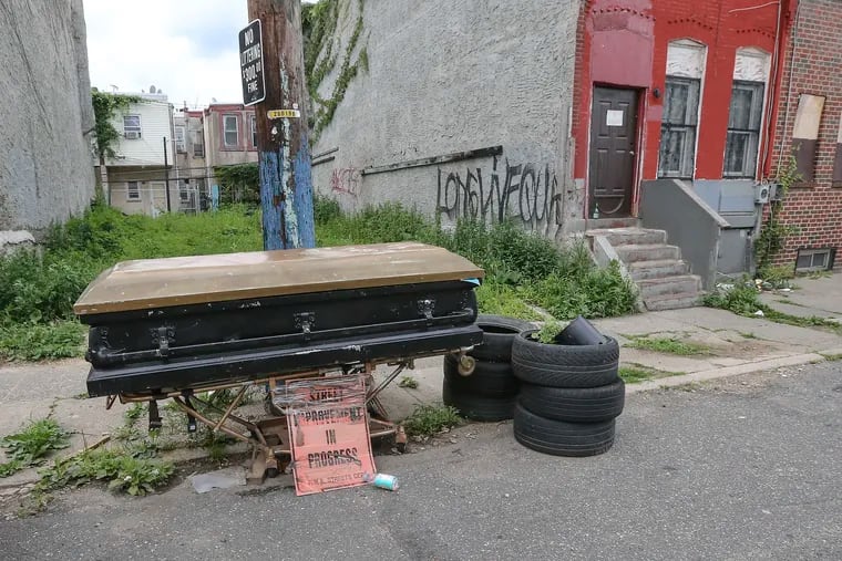 An empty casket sits chained to a telephone pole near 16th and Lehigh with a sign that reads "Street Improvements in Progress."