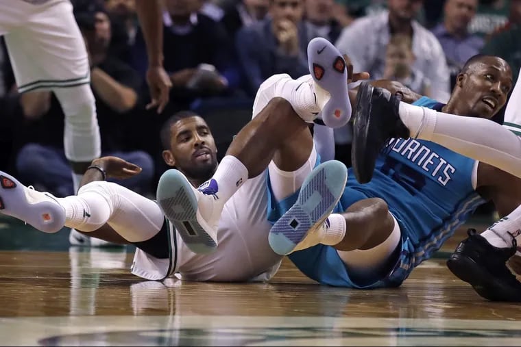 Boston Celtics guard Kyrie Irving, left, and Charlotte Hornets center Dwight Howard become entangled while chasing a loose ball Monday during a preseason game.