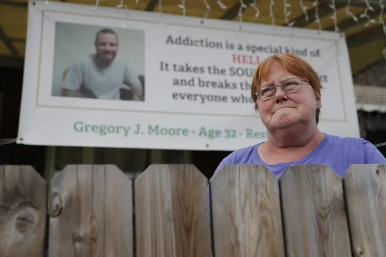Kathleen Deacy Moore, whose son, Gregory Moore, died of a heroin overdose earlier this year, hung a banner about her son’s death in front of her house.
