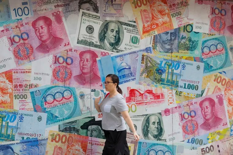 A woman walks by a money exchange shop decorated with different countries currency banknotes at Central, a business district in Hong Kong, Tuesday, Aug. 6, 2019. China's yuan fell further Tuesday against the U.S. dollar, fueling fears about increasing global damage from Beijing's trade war with President Donald Trump. (AP Photo/Kin Cheung)