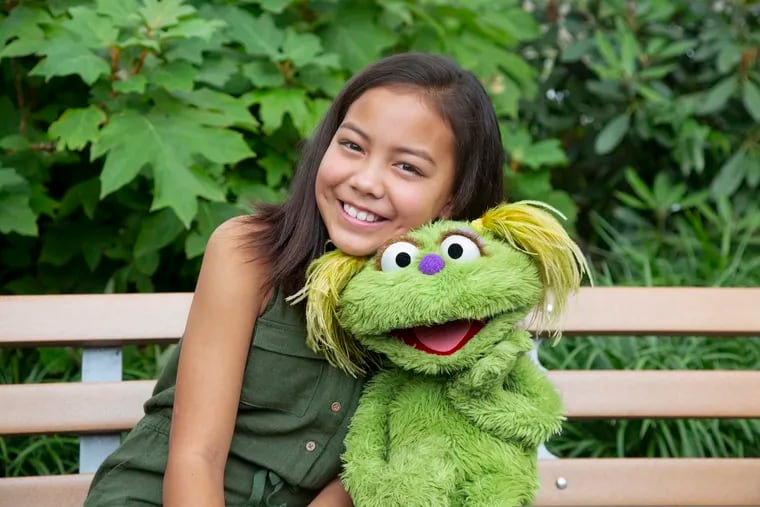 This undated image released by Sesame Workshop shows 10-year-old Salia Woodbury, whose parents are in recovery, with "Sesame Street" character Karli. Sesame Workshop is addressing the issue of addiction. Data shows 5.7 million children under 11 live in households with a parent with substance use disorder. Karli had already been introduced as a puppet in foster care earlier this year but viewers now will understand why her mother had to go away for a while.