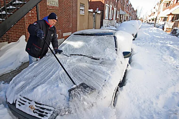 Sam Costilano, of the 1100 block of Daly Street in South Philadelphia,
uses a broom to clear snow from his car Sunday morning. The street had not been plowed and had snow drifts of more than 3 feet.
(Michael Bryant / Staff Photographer)