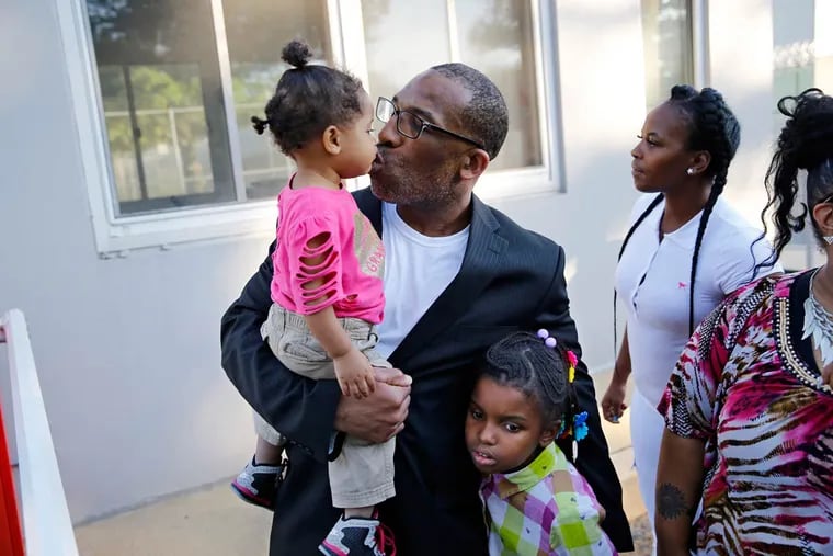 Anthony Wright steals a kiss from his granddaughter Romera Wright, 1, and holds on tight to his other granddaughter, Daria Wright, 8, as he spends time with his family after walking out of Curran-Fromhold Correctional Facility on Tuesday, Aug. 23, 2016.