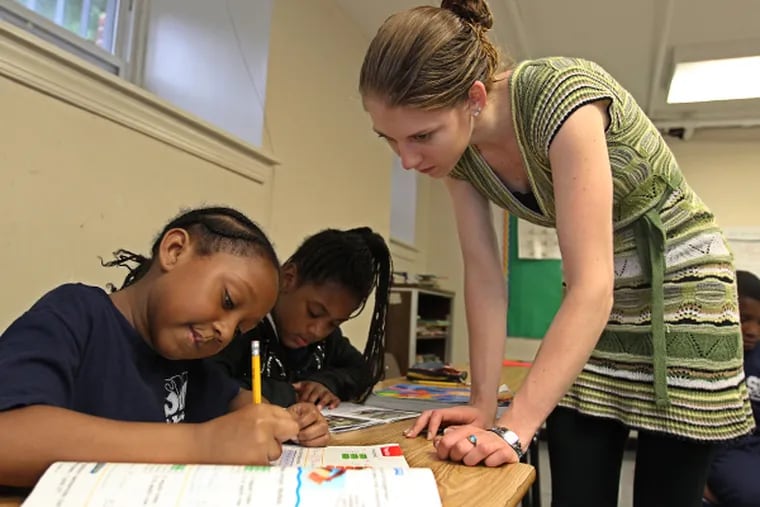 Second-grade teacher Nora Young, right, looks over the shoulder of Sanaa Payne, 8, as she works on a math problem in class Thursday, June 11, 2014, at St. Malachy School. The Archdiocese of Philadelphia's fledgling network of Catholic elementary schools in impoverished neighborhoods is embarking on an ambitious undertaking. (MICHAEL BRYANT/Staff Photographer)