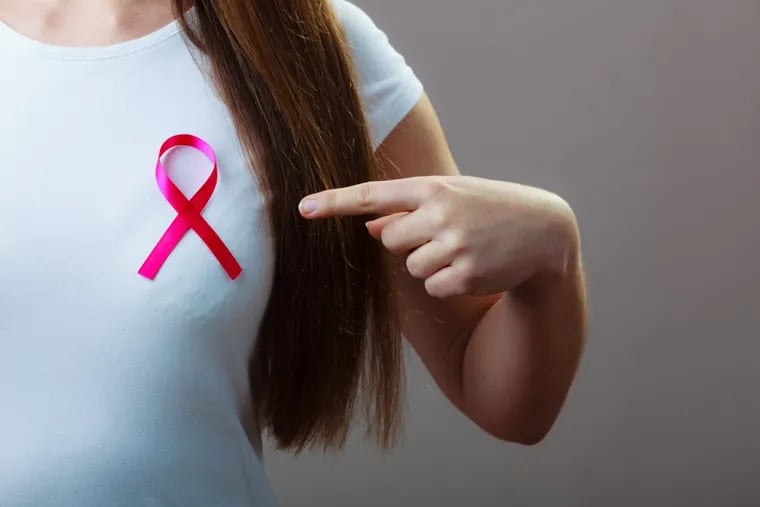 A woman wears a ribbon for breast cancer awareness.