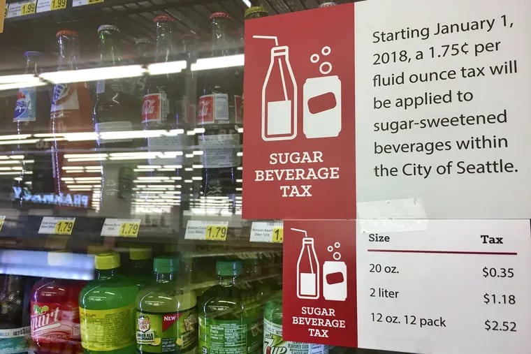 In this Sept. 24, 2018, a sign posted on a drink cooler in a store gives information about a soda tax that took effect in January, in Seattle. Washington voters last week approved a statewide ballot measure that bans new taxes on soda and other groceries. Seattle's tax remains in effect.
