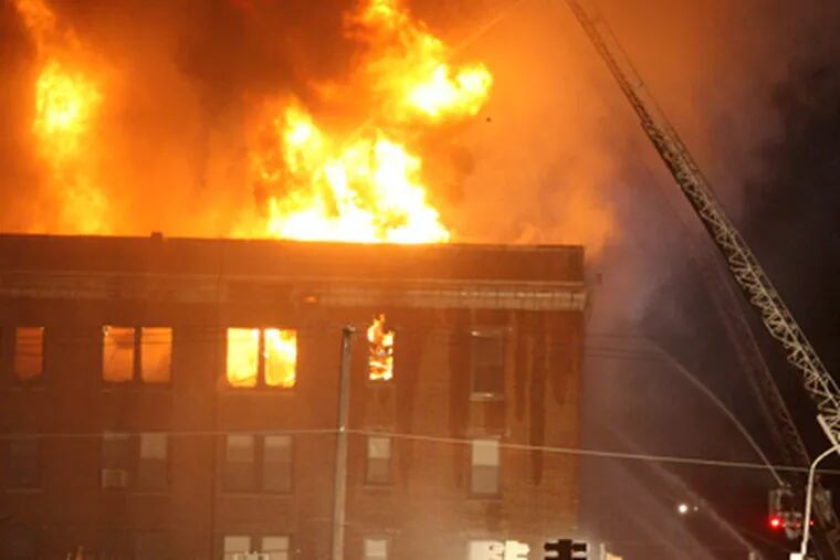 A fire in an apartment building on Walnut St. between 48th and Hanson streets burned into the evening. (Charles Fox / Staff Photographer)