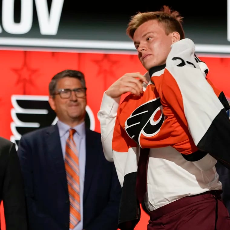 Matvei Michkov puts on a Flyers jersey after being picked by the team in the first round of the 2023 NHL draft.