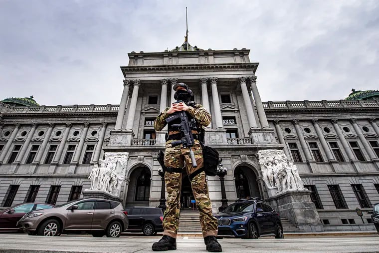 A member of the Pennsylvania Capitol Police stands guard at the entrance to the Pennsylvania Capitol Complex in Harrisburg, Pa., Wednesday, Jan. 13, 2021. State capitols across the country are under heightened security after the siege of the U.S. Capitol last week.
