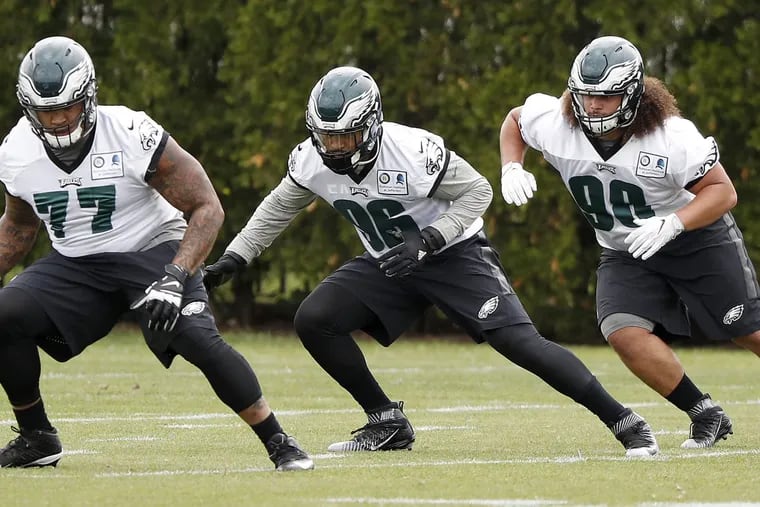 The Eagles’ Elijah Qualls (right) warms up with teammates (from left) Charles Walker, and Derek Barnett during rookie camp in May.