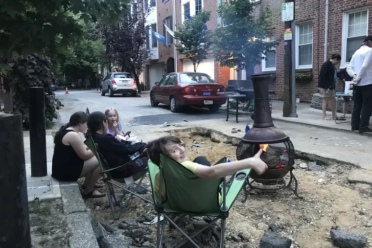 The sinkhole on the 1100 block of Rodman Street, which has been filled but not paved, has become a gathering place for impromptu parties on the block since it appeared in April.