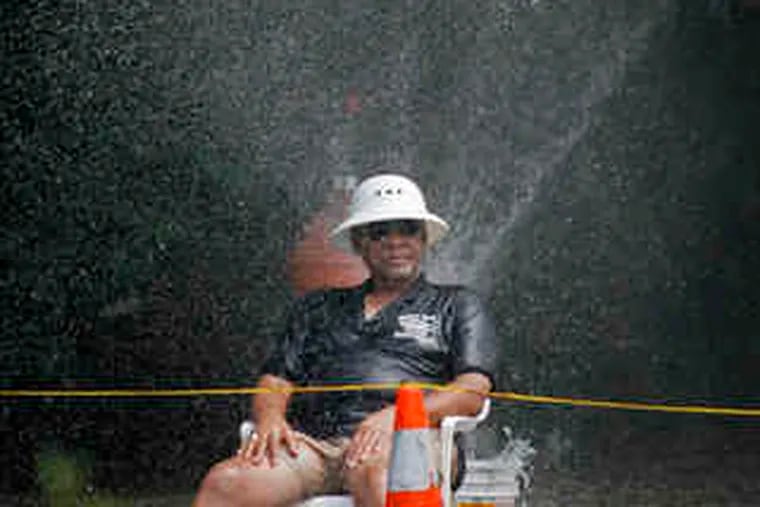 William Robbins, 71, of Southwest Philadelphia, sits in the mist of an open hydrant at 46th and Paschall.