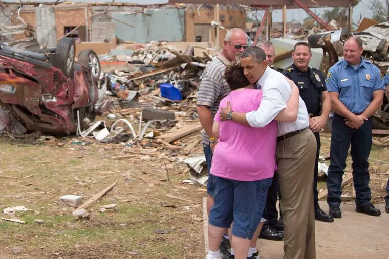With tornado devastation as a backdrop , in Moore, Okla., President Obama embraces Julie Lewis as her husband, Scott, watches. Their son, Zach, is a student at a school that was destroyed. The president promised federal support for rebuilding. Story, A2. CAROLYN KASTER / Associated Press