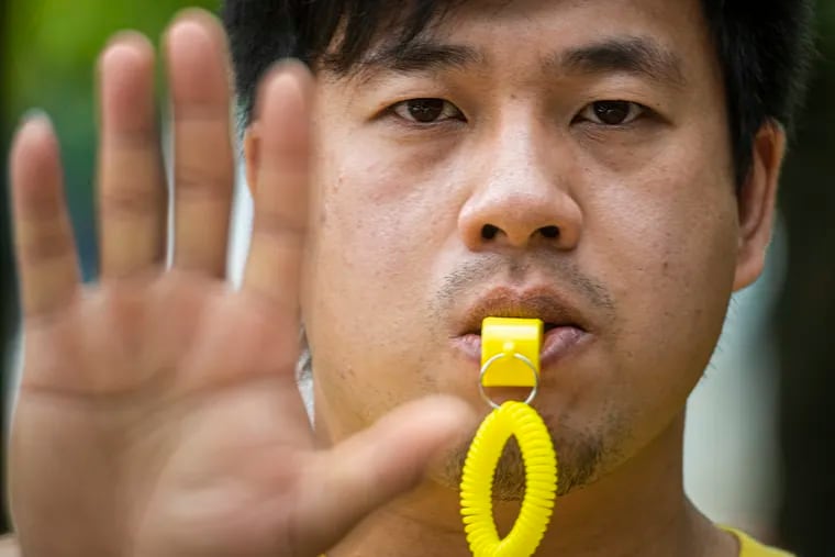 Wei Chen, civic-engagement coordinator for Asian Americans United, is photographed with a yellow whistle in West Philadelphia on Tuesday. The Philadelphia-based organization is handing out the whistles as part of a national campaign to increase safety for Asian Americans, who have been attacked on city streets from Philadelphia to San Francisco.