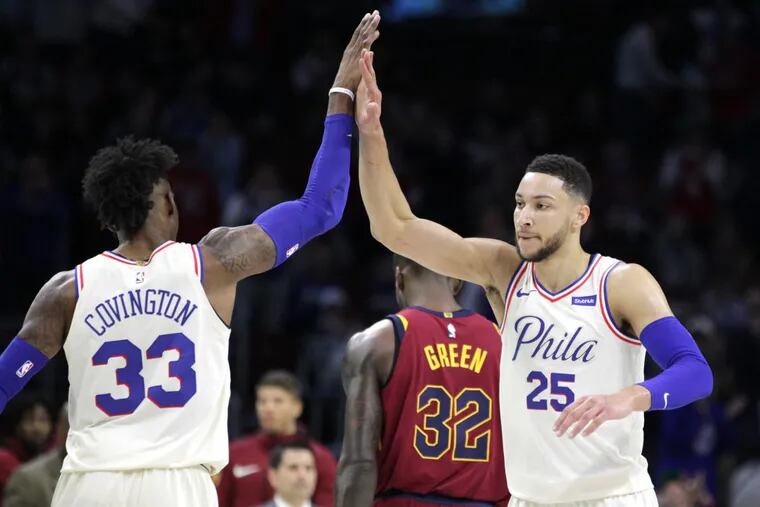 Ben Simmons (right) high-fiving teammate Robert Covington during a run against the Cavaliers on Friday.