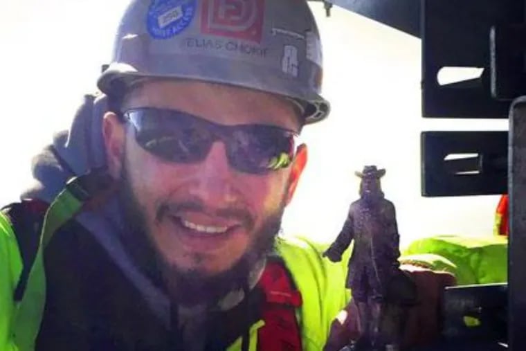 Elias Chokif, assitant superintendent with LF Driscoll, poses with the Billy Penn statue on the top steel beam of the new Comcast tower.