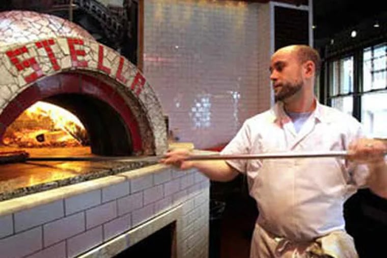 Sous chef Matt Conover keeps a safe distance from Pizzeria Stella's wood-burning oven as he pulls a finished pie from it.