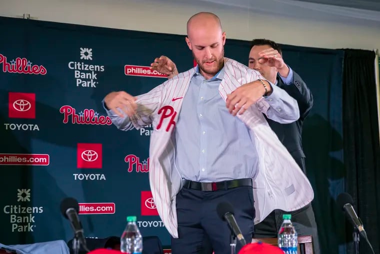 New Philadelphia Phillies pitcher Zack Wheeler gets help putting on his new uniform from Phillies general manager Matt Klentak, right, during a news conference Monday.