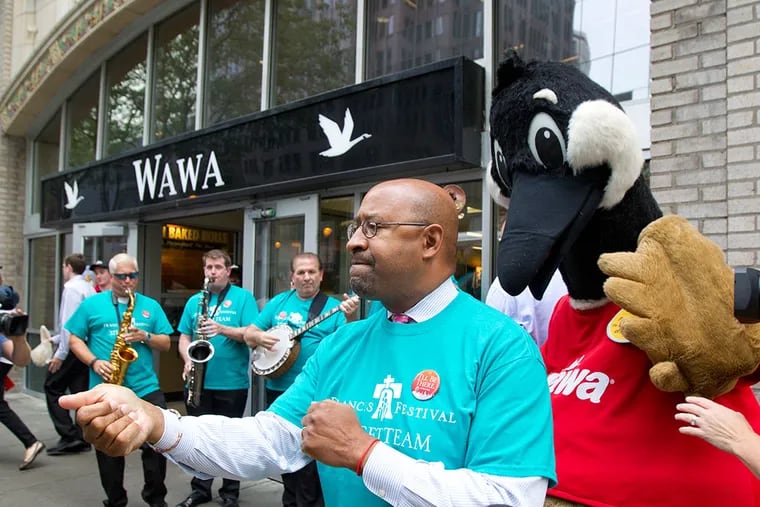 World Meeting of Families volunteers and Mayor Michael Nutter, center, distributed "OpeninPHL" kits to businesses. Nutter also does a few dance moves with the Wawa mascot, Wally. ( CHARLES FOX / Staff Photographer )