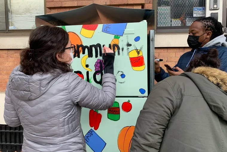 Volunteers help beautify the community fridge that was located in front of Bebashi in Spring Garden.