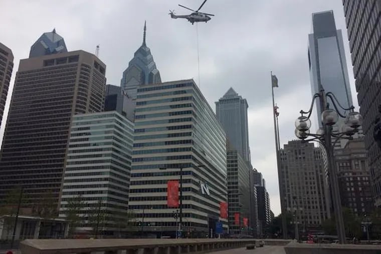 An "N" from the iconic "PNB" letter atop One South Broad Street dangles from a helicopter over 15th Street next to City Hall during a lift operation in 2014.
