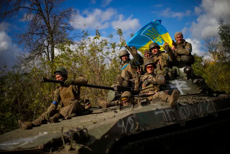 Ukrainian soldiers sitting on an armored vehicle as they drove on a road between Izium and Lyman in Ukraine on Tuesday.