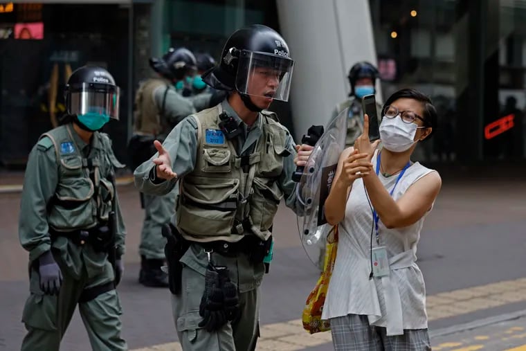 Riot policeman pushes a woman as she is taking a photograph of the detained protesters at the area in Mongkok, Hong Kong. Secretary of State of Mike Pompeo has notified Congress that the Trump administration no longer regards Hong Kong as autonomous from mainland China.