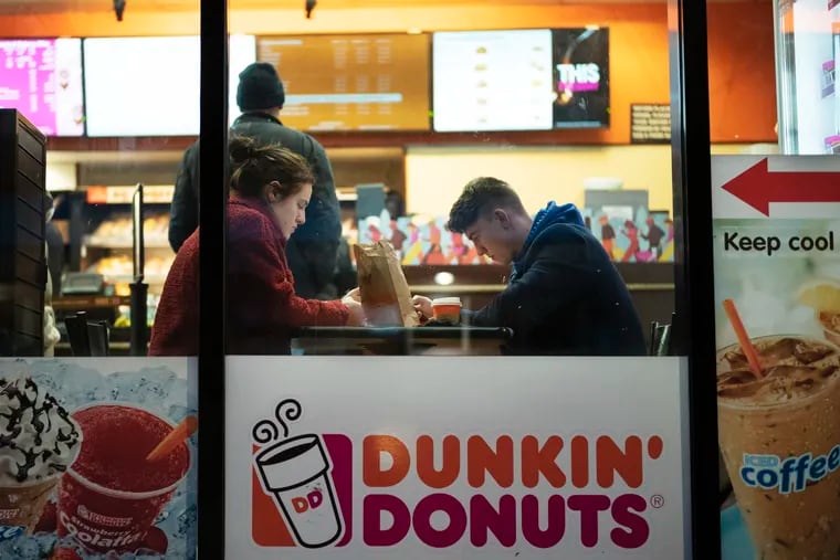 In this Jan. 30, 2019, file photo customers sit inside a Dunkin' Donuts in New York.