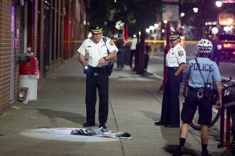 Philadelphia Police Inspector D. F. Pace looks over evidence at the scene of the shooting on South Street that left three dead and 11 wounded.