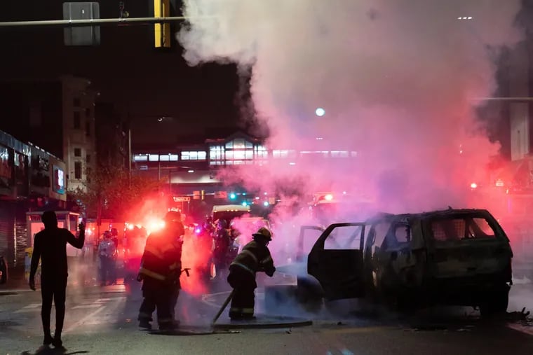 Firefighters put out a police car that was on fire near 52nd and Chestnut Street, Oct. 26, 2020, in Philadelphia.