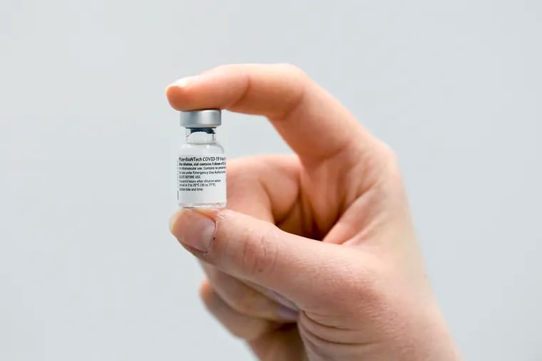 A woman holds the empty container of the first Pfizer/BioNTech coronavirus vaccine used in The Netherlands at a mass vaccination center in Veghel, Wednesday Jan. 6, 2021.