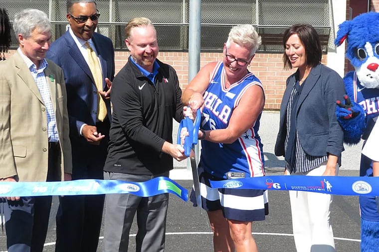Sixers president Chris Heck (center, left) and Cooper's Poynt School principal Janine Casella shared ribbon-cutting duties during the dedication of the revitalized basketball court at the school in 2019.