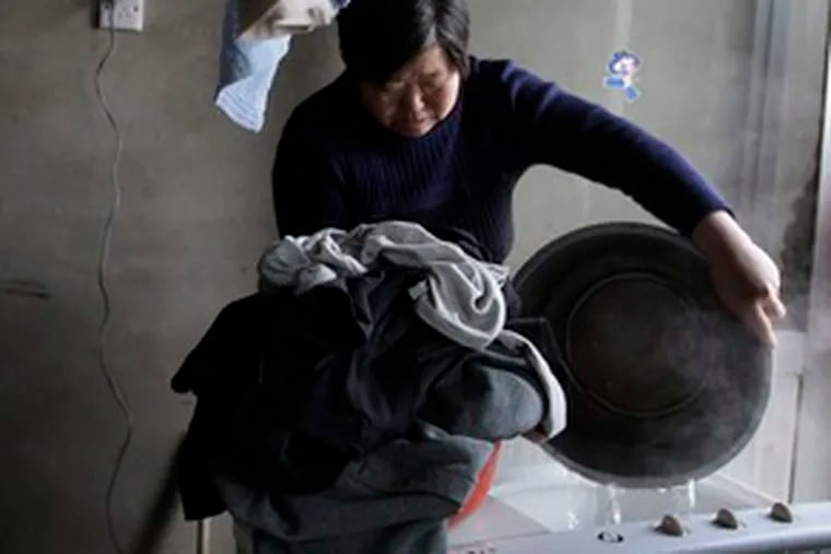A woman pours water into a washing machine to launder her clothes in Miyun, where Beijing&#0039;s receding main reservoir is located.