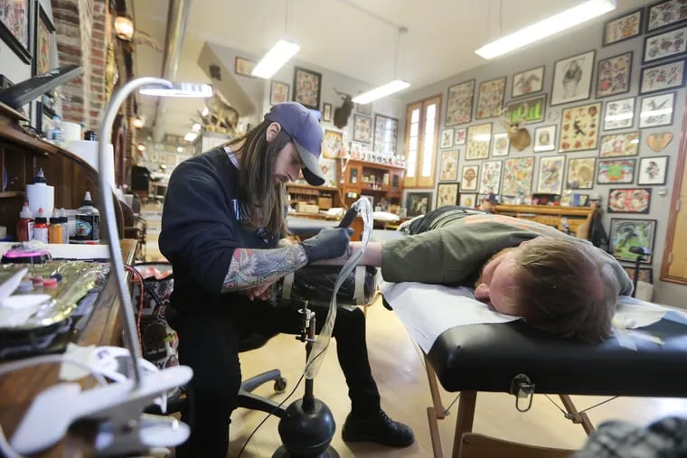 Ross Phillips tattoos a red-tailed hawk on Edward Dearinger, at Seven Swords Tattoo Company. He used his $500 tax return to pay for it.