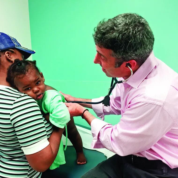 Pediatrician Dan Taylor examines a young patient, Jaleene, recently at the primary care clinic at St. Christopher's Hospital for Children.
