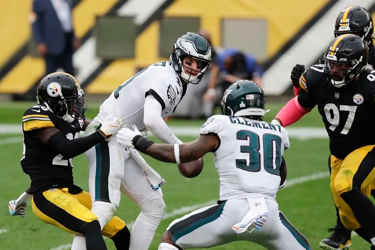 Eagles quarterback Carson Wentz tries to get rid of the football against the Steelers' defensive rush in Sunday's 38-29 loss.