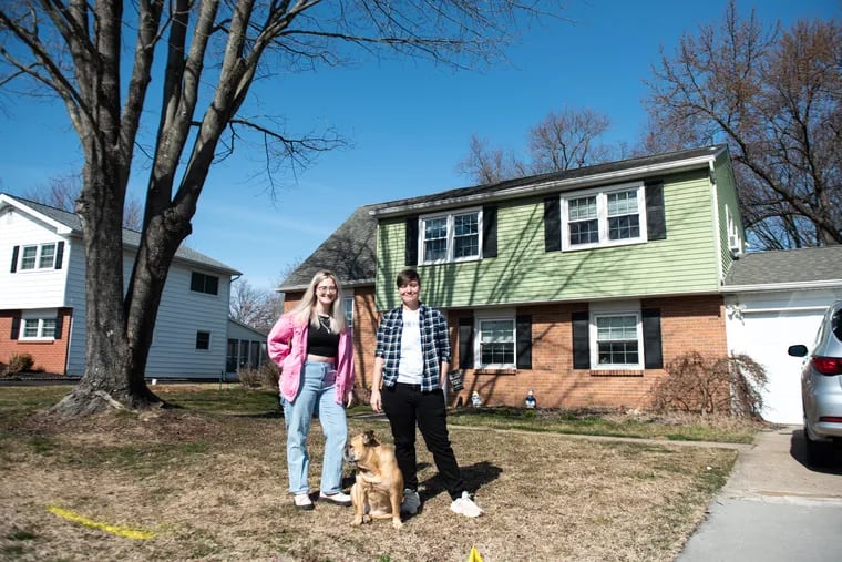 Mel and Rel Kulenski pose for a portrait with their dog, Winston, in front of their home in Morrisville, Pa. on Saturday, Feb. 24, 2024. Mel Kulenski’s late father, Richard Schatz, planted the tree on the front lawn years ago when he lived in the house.