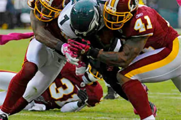 Eagles quarterback Michael Vick is smashed by Redskins DeAngelo Hall (left) and Kareem Moore. The first-quarter play ended Vick’s day. (Clem Murray / Staff Photographer)