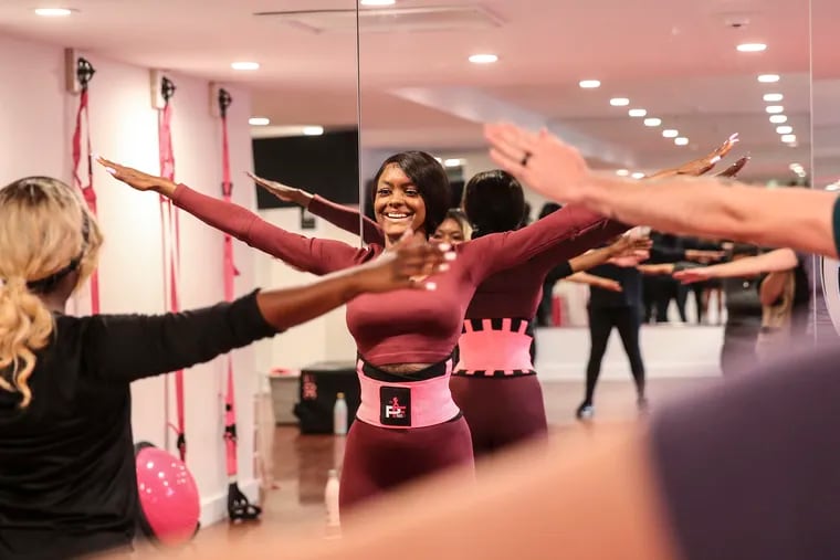 Noel Davis center, is teaching a barre class at her studio at 221 Vine Street, with most members attending in person and some still attending virtually on Zoom.