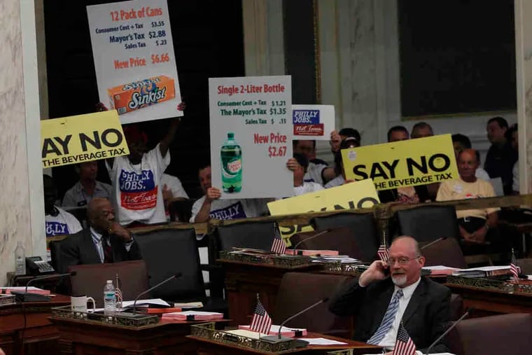 With protesters in the background, Councilman William K. Greenlee (right) participates in a Council hearing on the proposed soda tax.
