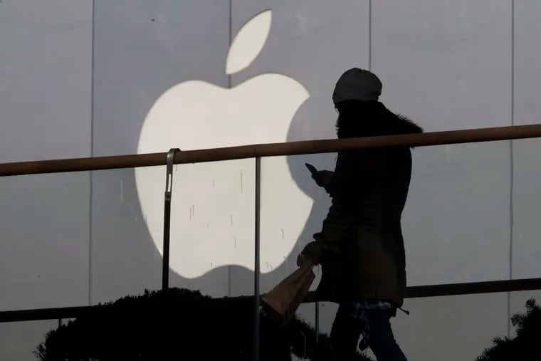 Awoman using a phone walks past Apple's logo near its retail outlet in Beijing in Dec. 2013. The FBI is asking Apple to help extract data from iPhones that belonged to the Saudi aviation student who fatally shot three sailors at a U.S. naval base in Florida in December 2019.
