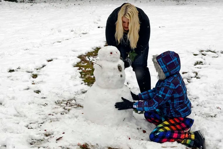 Sisters Viktoria, 19, and Antionette Ziegler, 11, building a snowman Tuesday near their home in Haddonfield.