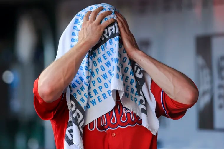 Philadelphia Phillies' Spencer Howard covers his face with a towel in the dugout after leaving a baseball game during the third inning against the Cincinnati Reds in Cincinnati, Monday, June 28, 2021. (AP Photo/Aaron Doster)