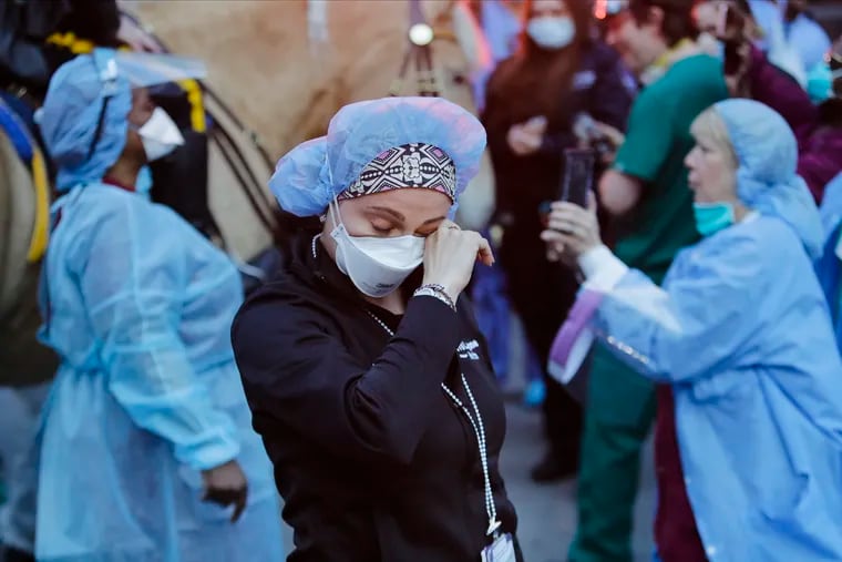 A medical worker reacts as police officers and pedestrians cheer medical workers outside NYU Medical Center in New York on April 16. Such displays, says the writer, feel like 2 million people hugging each other virtually.
