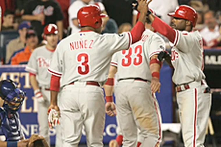 Jimmy Rollins, right, celebrates with teammates Aaron Rowand (33) and
Abraham O. Nunez (3) after hitting a three-run home run during the seventh inning on Wednesday at Shea Stadium.