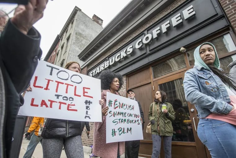 Soren McClay (left) and her stepmother, Donn T, hold signs during a Black Lives Matter demonstration in front of the Starbucks at 18th and Spruce Streets in April.