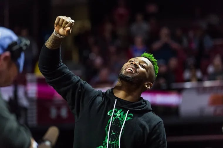 Eagles player Jalen Mills pumps a fist in the air as he’s honored at the Temple vs UCF game at the Liacouras Center on Sunday.